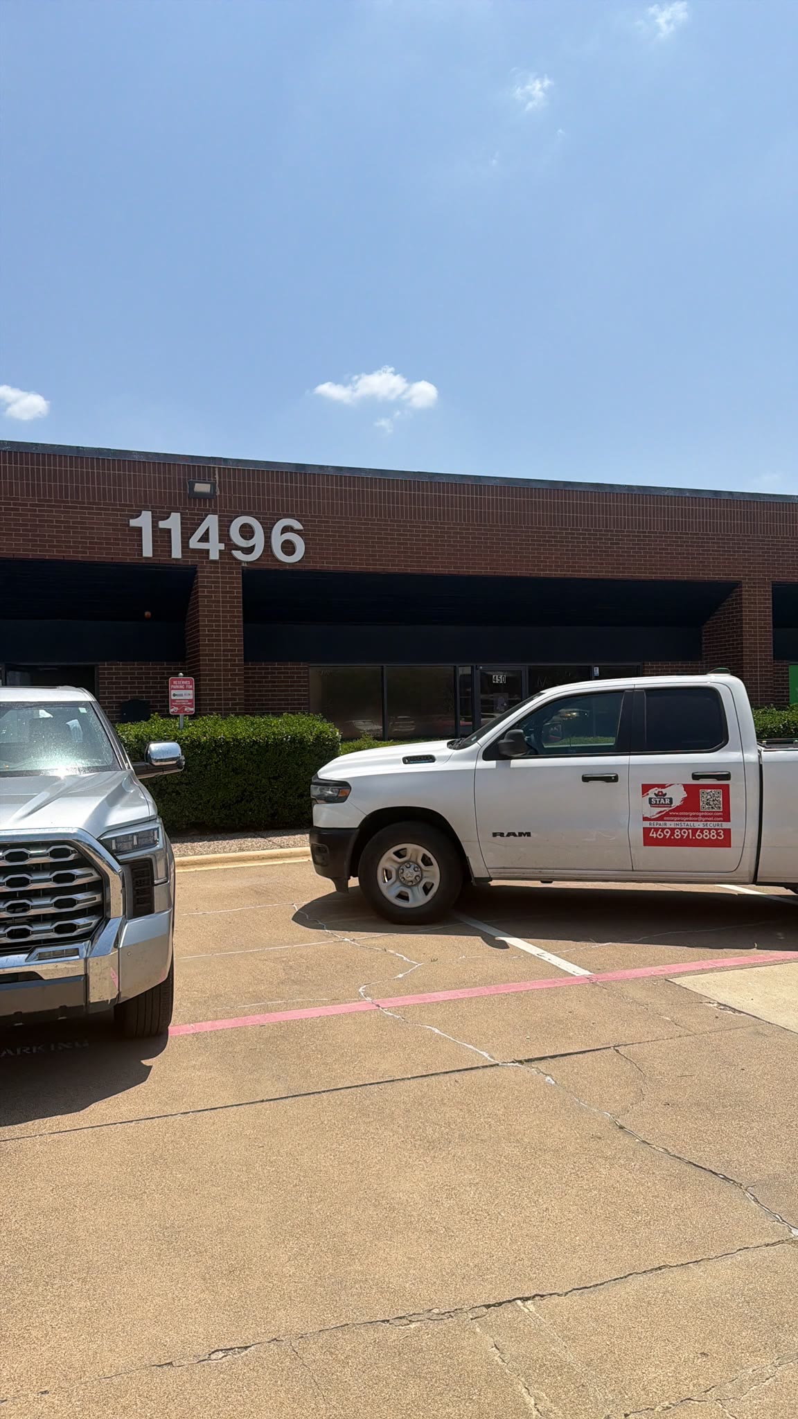 White A Star Garage Door Repair service pickup parked outside the company's single-storey brick office building on a clear day.